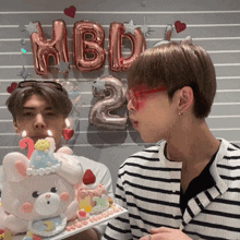 a man blowing out candles on a cake that says 2 on it
