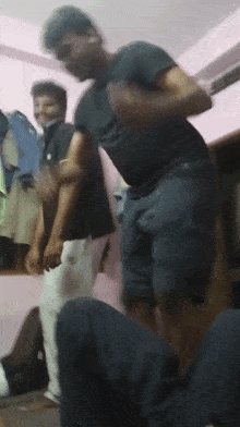 a man in a black shirt is dancing in a room with other men