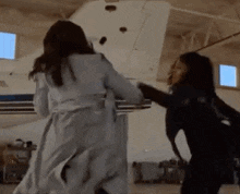 two women are standing next to each other in front of a plane in a hangar .