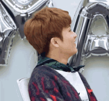 a man wearing a sweater that says carhartt is sitting in front of balloons