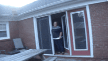 a woman stands in a doorway of a brick house