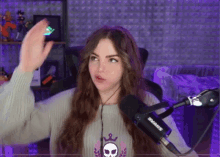 a woman wearing a sweater with a skull on it is standing in front of a shure microphone