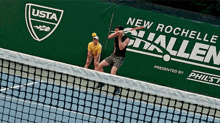 two men are playing tennis in front of a banner that says " new rochelle hallen "