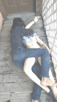 a woman is laying on a man 's lap on a wooden deck