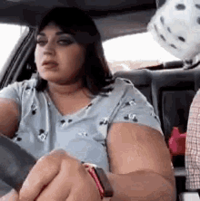 a woman is sitting in the driver 's seat of a car with a stuffed animal in the back seat .