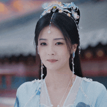a woman wearing a blue and white dress with pearls and a tiara