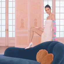 a woman in a white dress is sitting on a blue couch in a room .