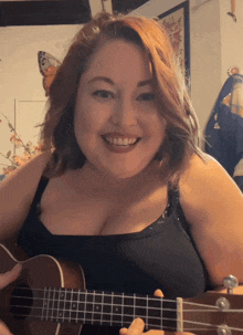a woman with red hair is smiling while holding a guitar