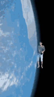 a man in a black shirt is holding a baby in front of a blue planet