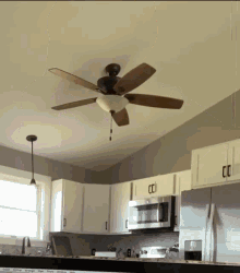 a kitchen with white cabinets and a ceiling fan with a light