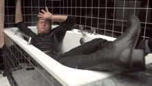 a man is laying in a bathtub with his legs up