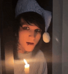 a person wearing a hat and holding a candle