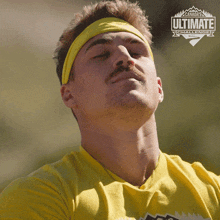 a man wearing a yellow shirt and a yellow headband with the word ultimate on it