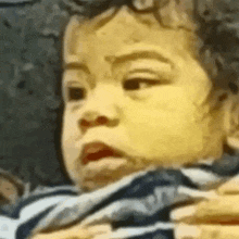 a close up of a baby making a funny face while being held by a person .