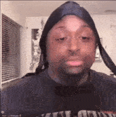 a man wearing a head scarf and a black shirt is making a funny face .