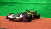 a purple and yellow toy race car is sitting on a table in front of a green screen .