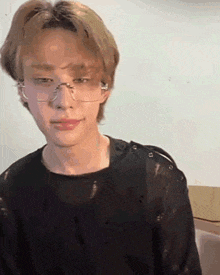 a young man wearing glasses and a black shirt looks at the camera