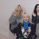 a group of women are sitting in a room and one of them is wearing a sweatshirt that says dream on it .