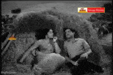 a man and a woman are sitting next to each other in a field of hay .