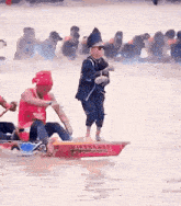 a man is standing on a boat in the water while a group of people are rowing boats .