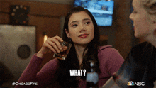 a woman is holding a glass of whiskey and the word what is above her