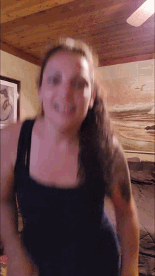 a woman in a black tank top is dancing in a room