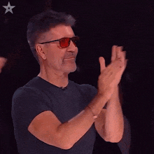 a man wearing sunglasses and a black shirt is applauding
