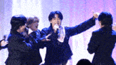 a man singing into a microphone surrounded by three other men