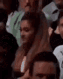 a woman is sitting in a crowd of people watching a game .