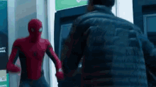 a man in a spiderman suit is standing next to a man in a black jacket .