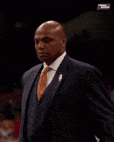 a man in a suit adjusts his tie in front of a sign that says black madness