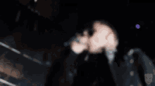 a man with a tattoo on his neck is standing in a dark room holding a microphone .
