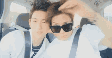 two young men wearing sunglasses are sitting in a car .