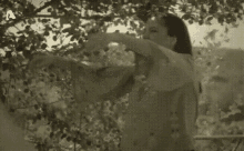 a black and white photo of two women standing under a tree with the letter a in the corner .