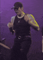 a man wearing a black tank top and a hat is dancing on a stage