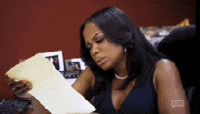 a woman is sitting at a desk looking at a piece of paper ..