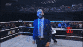 a man in a suit is dancing in a wrestling ring with a aew sign in the background