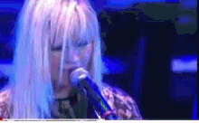 a woman singing into a microphone with a blurred background