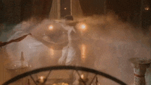 a man is dancing in a room with a lot of smoke coming out of the ceiling .