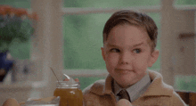 a young boy is sitting at a table with a jar of honey and eggs