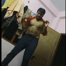 a shirtless man is standing in a room with clothes hanging on a rack