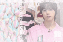 a man in a pink shirt is sleeping next to a pile of pink and blue marshmallows