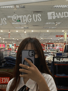a woman taking a selfie in front of a sign that says us @tag us