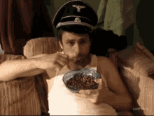 a man wearing a nazi hat is eating cereal from a bowl