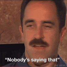 a man with a mustache has the words " nobody 's saying that " on his face