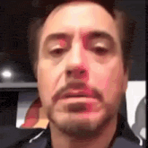 a close up of robert downey jr. 's face with a beard making a funny face .