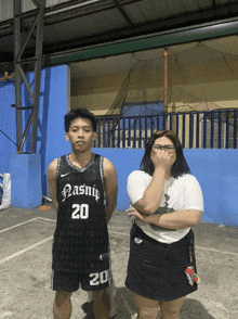 a man wearing a nasnip 20 jersey stands next to a woman