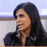 a woman with long black hair is making a funny face while sitting in front of a window .