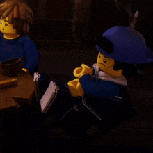 two lego figures are sitting at a table with a cup