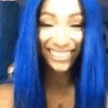 a woman with blue hair is smiling with her eyes closed and her mouth open .